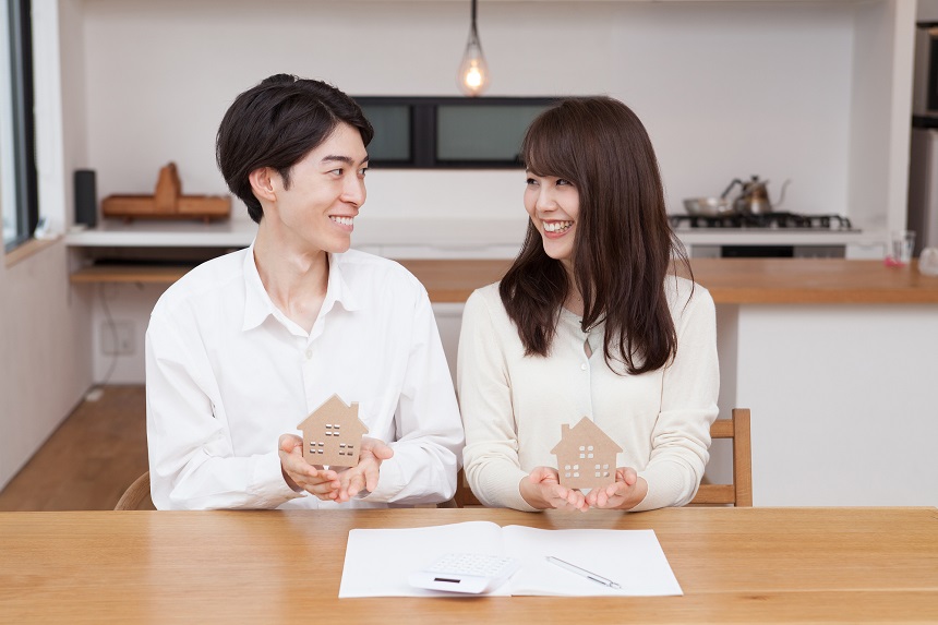 家の模型を持ちほほ笑みあう夫婦
